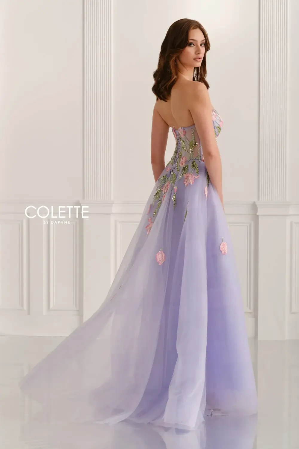 A woman wearing a strapless lavender gown with floral embellishments.