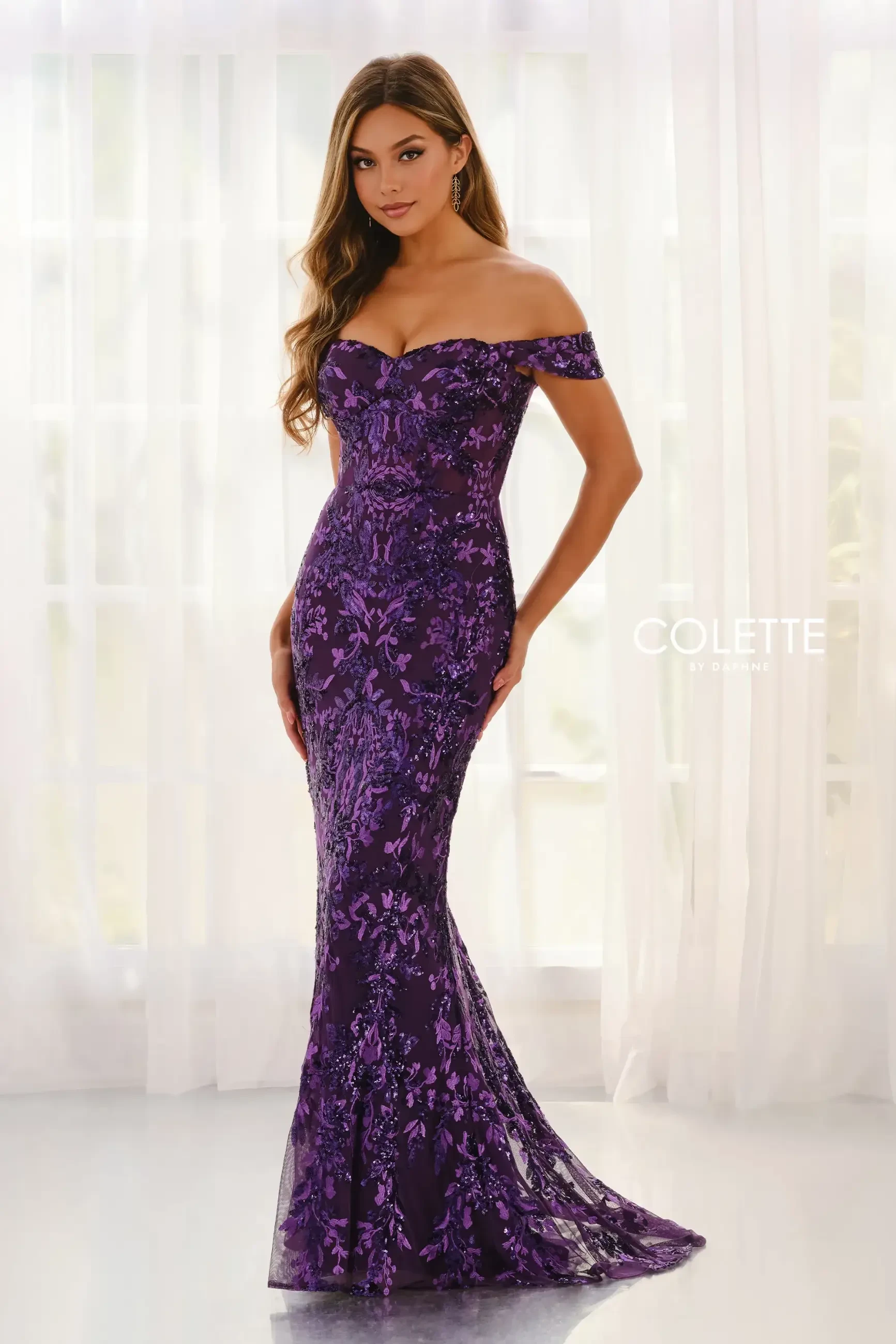 A woman in a stunning off-shoulder, purple floral lace gown stands gracefully. The elegant dress highlights a sophisticated and glamorous tone.