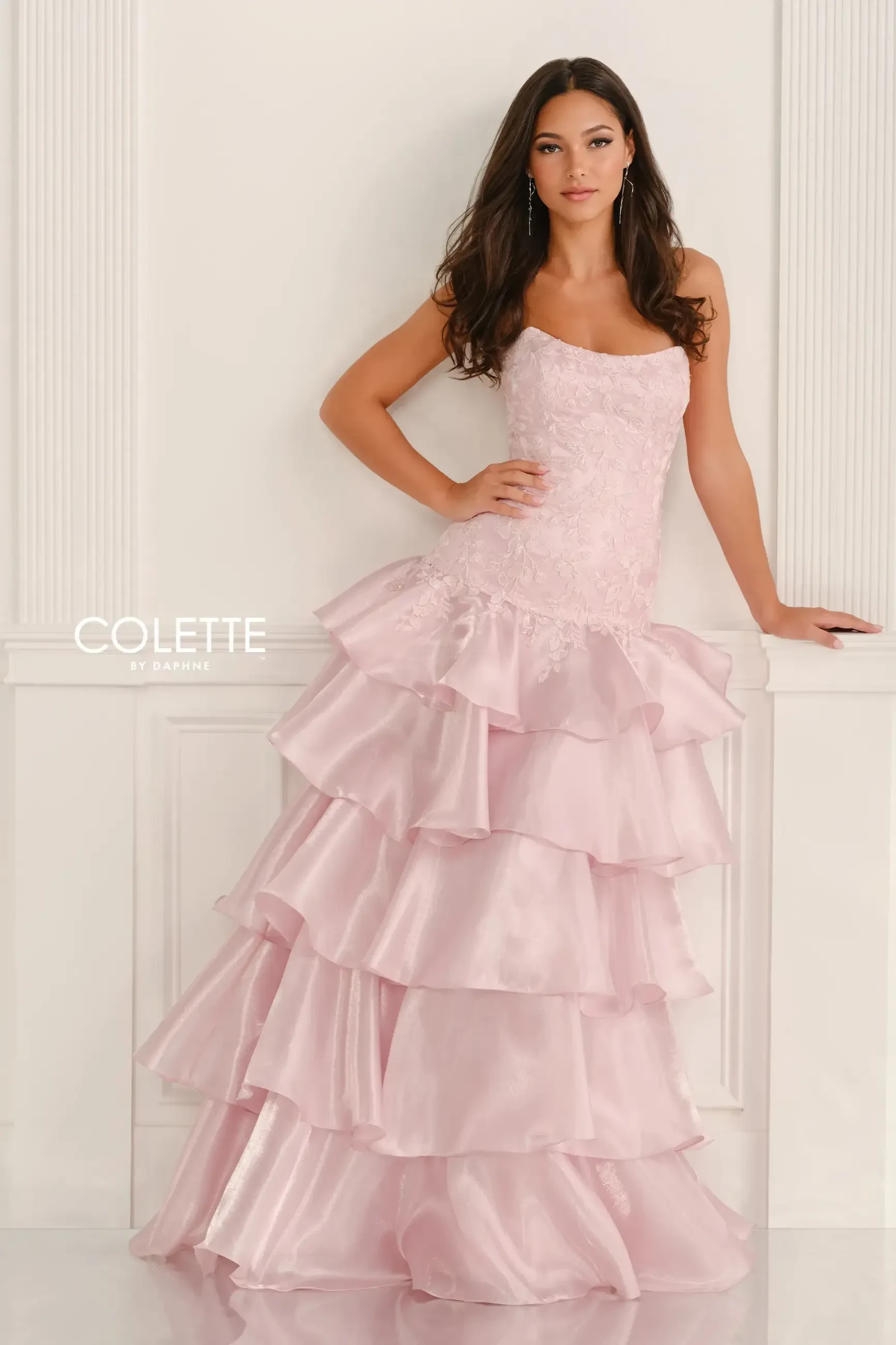 model is wearing a light pink tiered prom dress