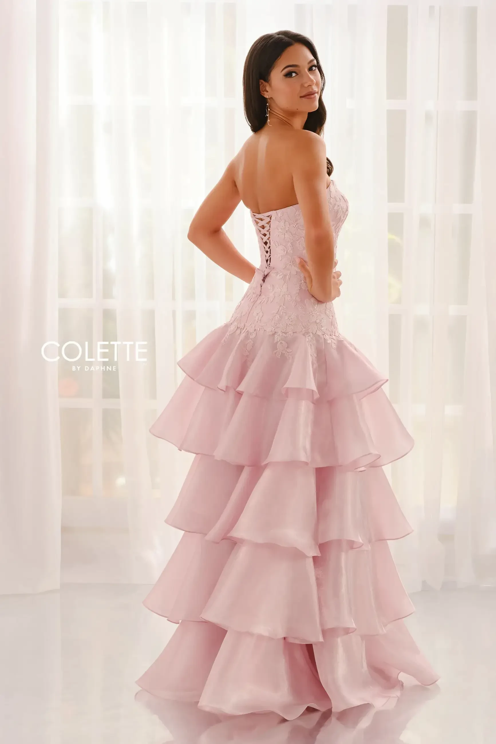 model is wearing a light pink tiered prom dress