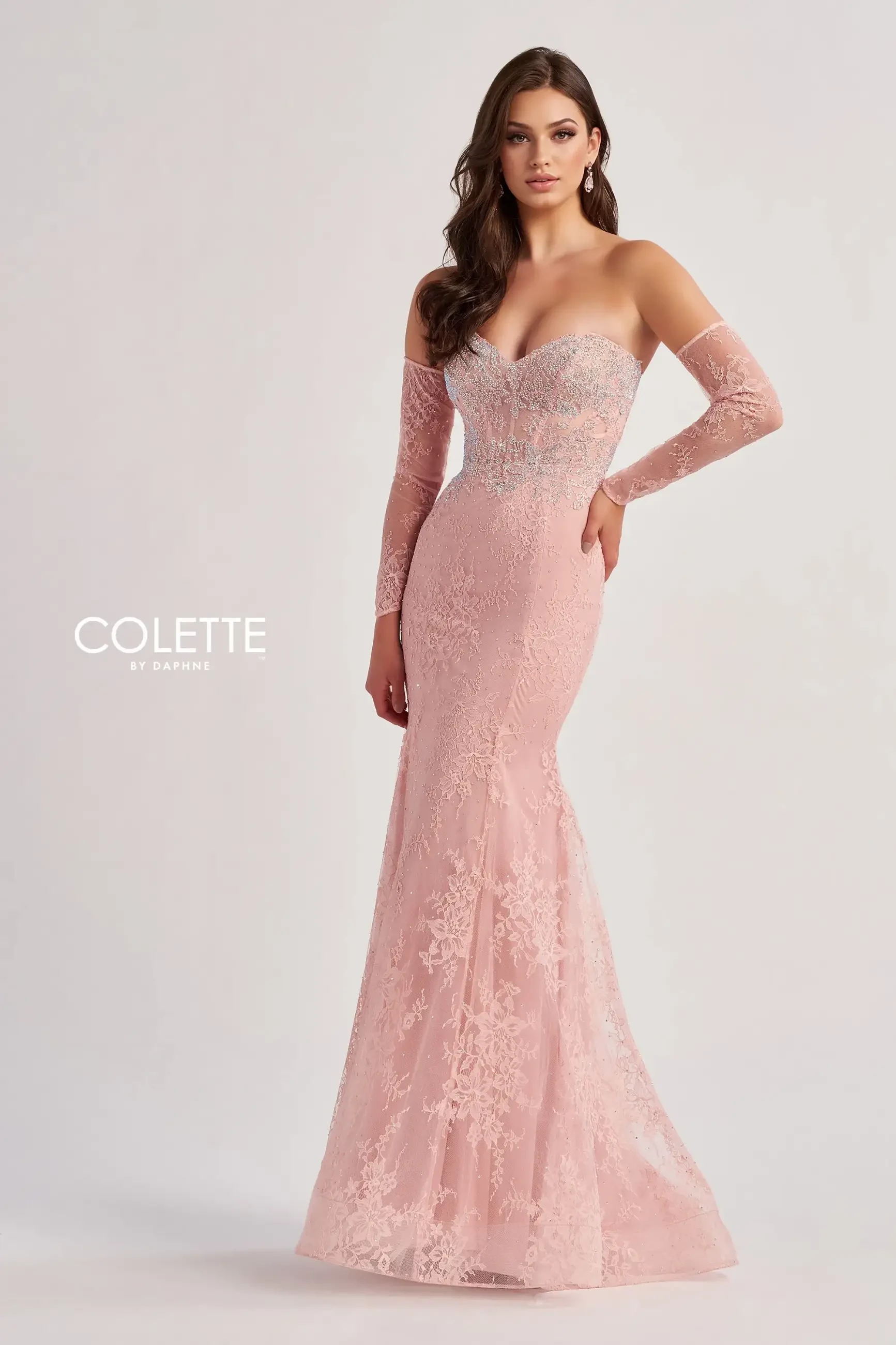 model is wearing a light pink fit and flare evening gown with detachable off the shoulder long lace sleeves