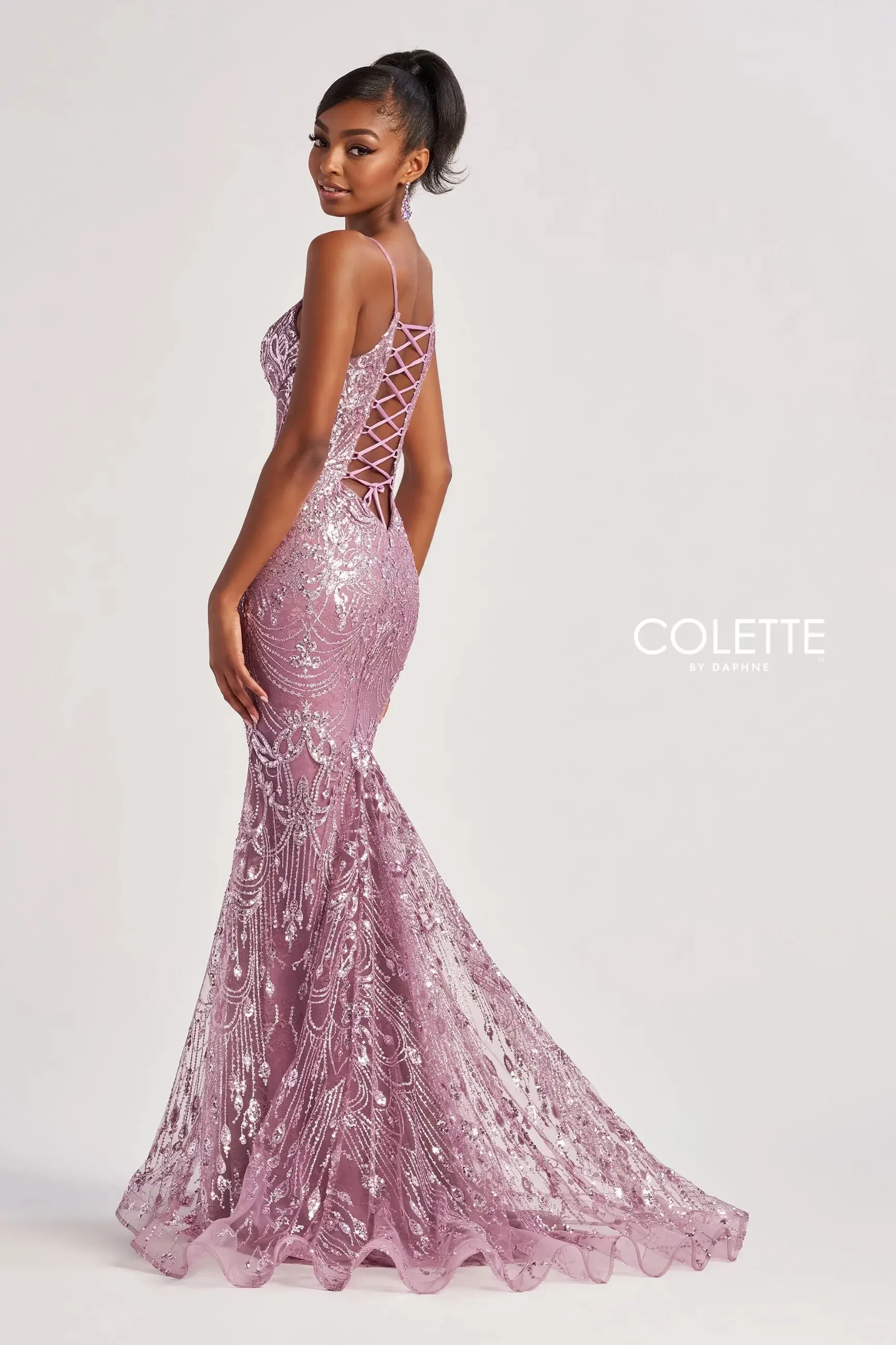 Model is wearing a sparkly evening dress with a mermaid silhouette and plunging neckline 