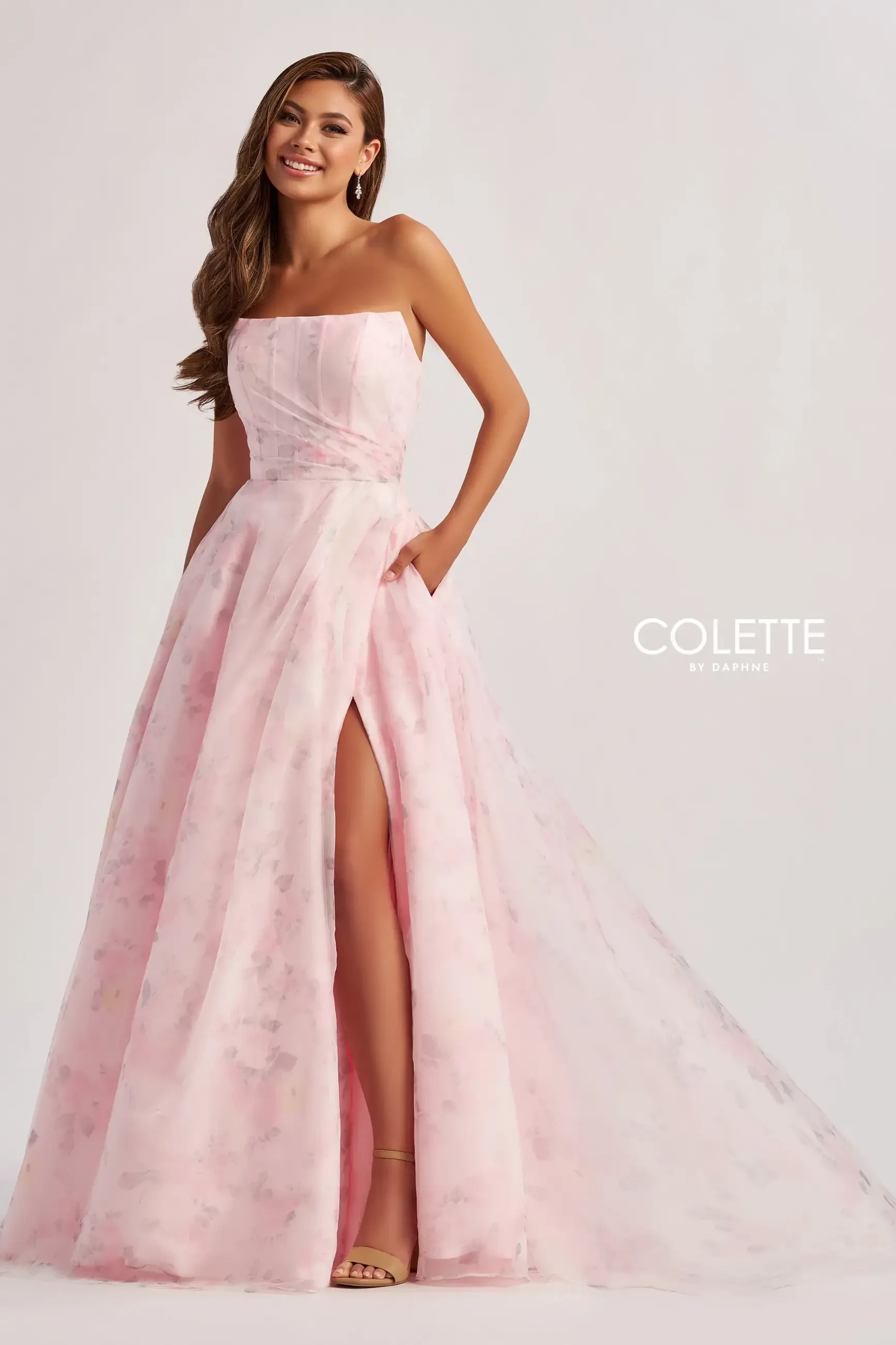 model is wearing a strapless light pink evening gown with a high slit