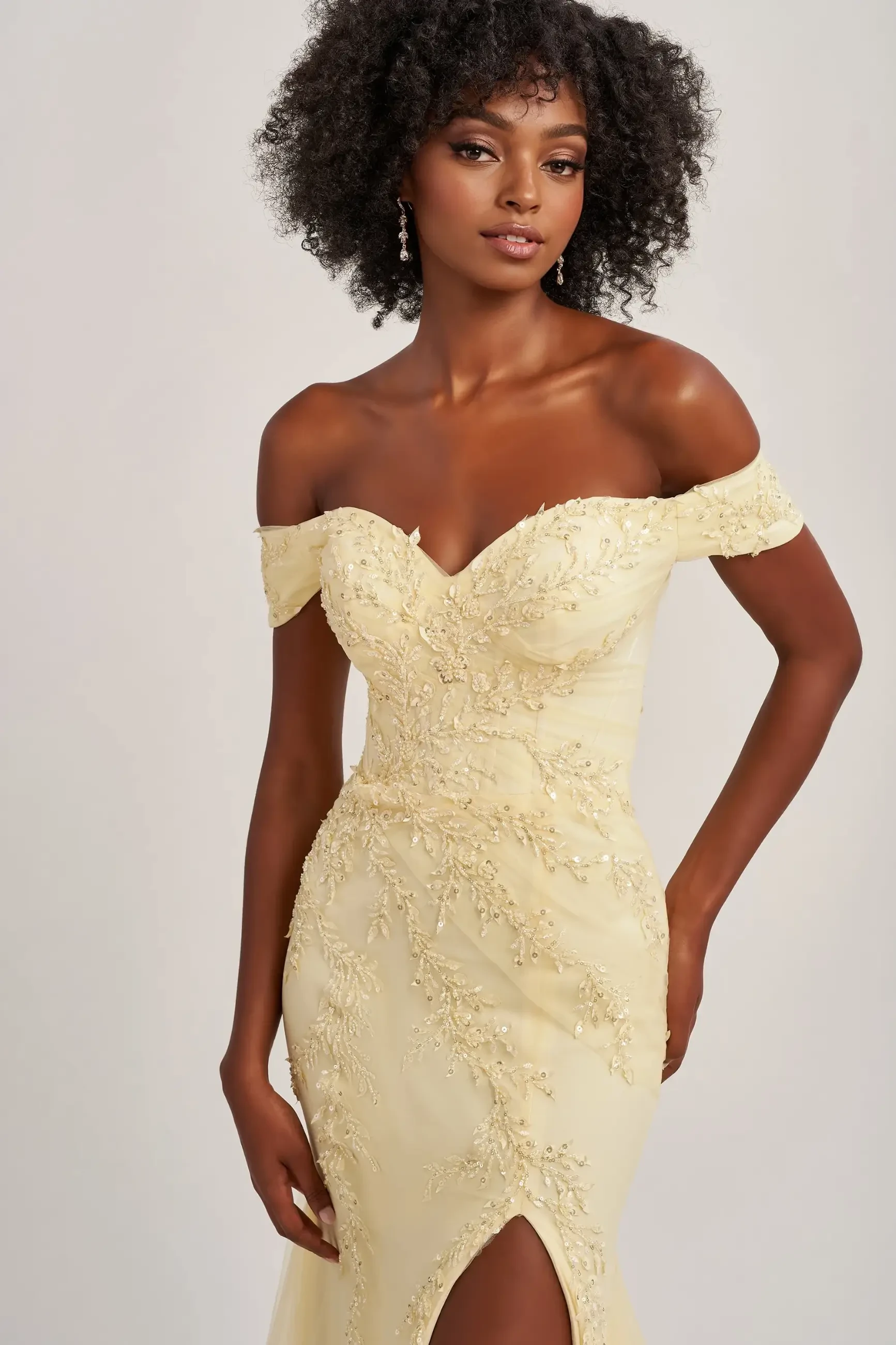 model is wearing a light yellow off the shoulder prom dress