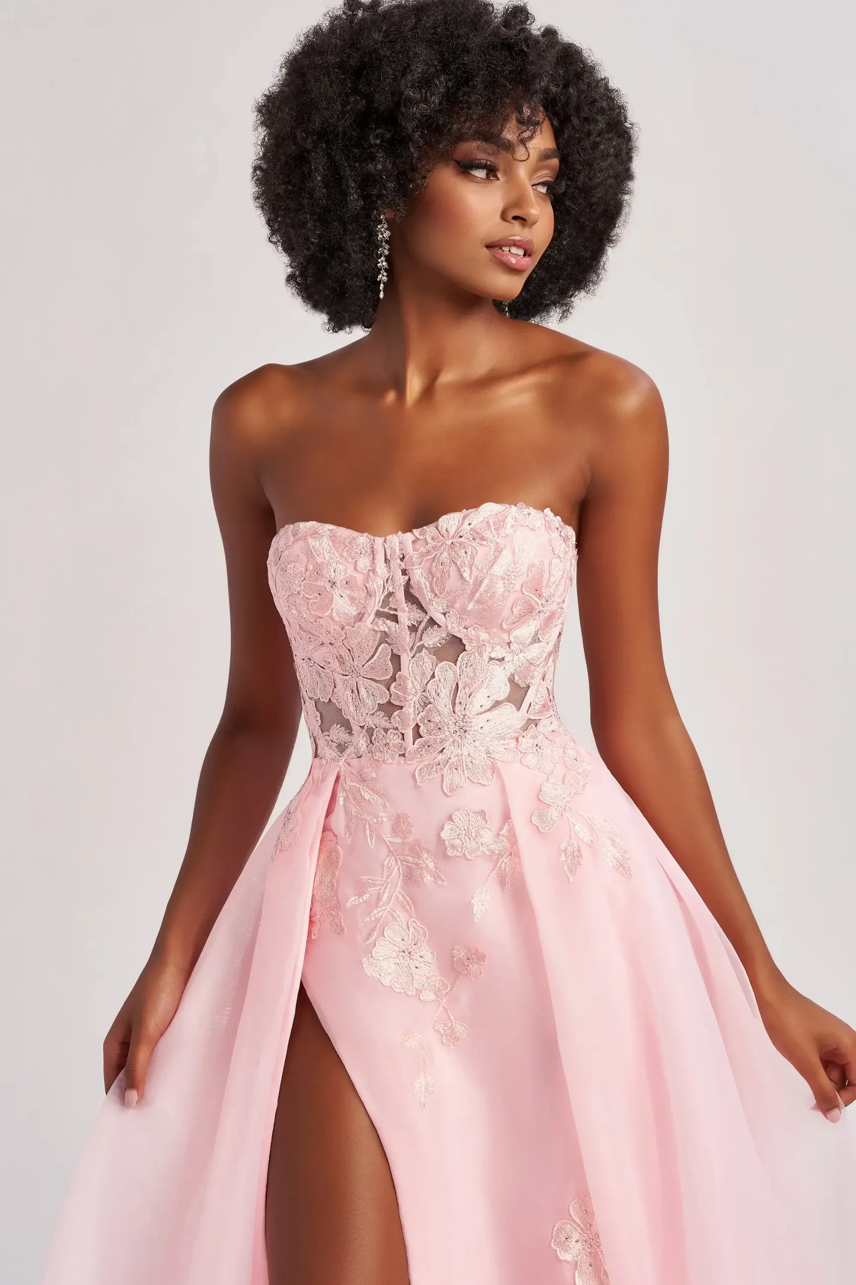 Model is wearing a strapless sweetheart a-line evening dress with a corset bodice